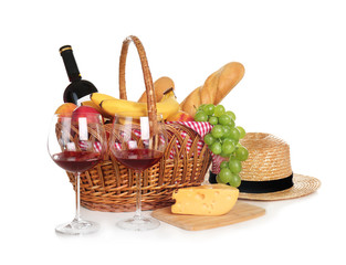 Picnic basket with food and glasses of wine on white background