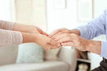 Helping hands on blurred background, closeup. Elderly care concept