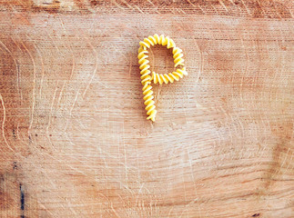 P letter done with pasta fusilli on a wooden chopping board