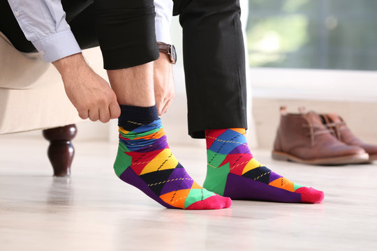 Man putting on stylish socks indoors, closeup