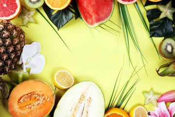 Assortment of tropical fruits with leaves of palm trees and exotic plants