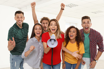 Group of happy young people with megaphone indoors