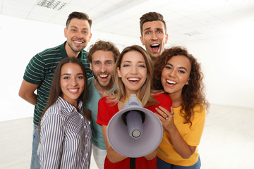 Group of happy young people with megaphone indoors