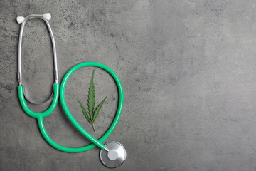 Stethoscope, hemp leaf and space for text on grey background, top view
