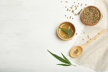 Rolgordijnen Hemp oil, seeds and space for text on white wooden background, flat lay © New Africa