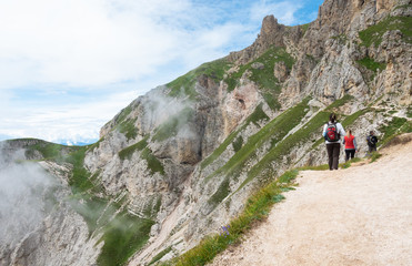 Three hikers going along a trail on mountain Sciliar