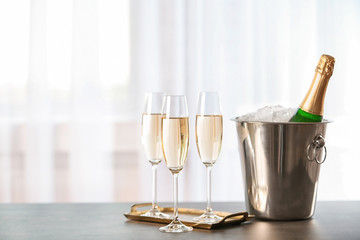 Glasses with champagne and bottle in bucket on table - Powered by Adobe