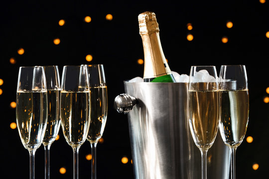 Glasses with champagne and bottle in bucket against blurred lights