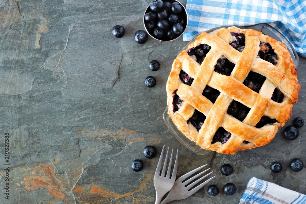 Poster Rustic homemade blueberry pie with lattice pastry. Top view scene. Side border with copy space over a dark stone background.
