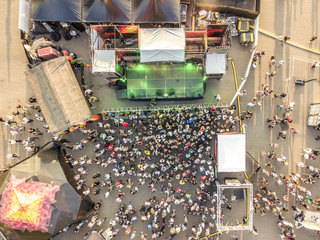 aerial top view of crowd of people standing near the stage on concert on summer day