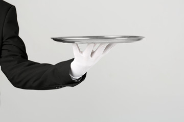 Waiter holding metal tray on light background