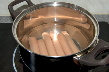 Pan with boiled sausages on the stove in the kitchen