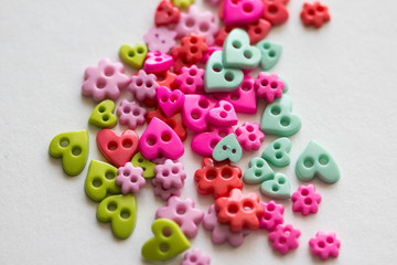 Mixed coloured bright buttons. Colored buttons in the shape of heart. Button plastic colorful on white background and copy space. Beautiful color buttons. Sewing buttons.  Many color plastic.