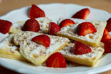 Waffles with sliced strawberries and powdered sugar