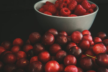 Raspberries and plums on a black table. Berries and fruit. 