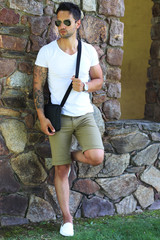 Handsome fashion man with a Satchel and sunglasses posing outdoor