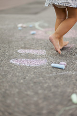 Kind malt mit Kreide auf Boden. Child draw with street crayon.