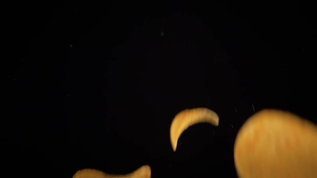 potato chips in free fall on a black background. Slow motion. The view from the side. Pringles