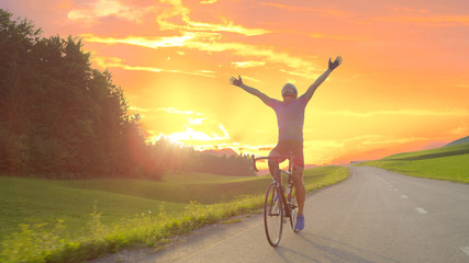LENS FLARE Thrilled bicycle rider celebrates win in bike race across countryside
