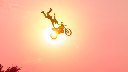 Extreme pro motocross biker jumping freestyle trick over the sun