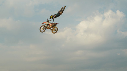 Professional biker jumps big air trick at dusty motocross circuit