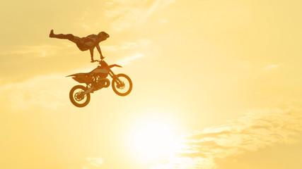 Obraz premium Pro freestyle motocross biker jumping extreme trick over sunset sky