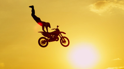 Extreme pro motocross biker jumping freestyle trick over the sun