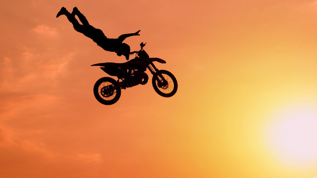 Extreme pro motocross biker jumping freestyle trick over the sun