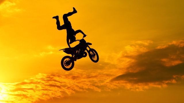 Extreme motocross biker jumping freestyle trick at sunset