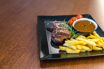 Steak with french fries on wooden table