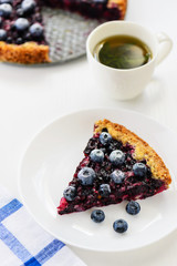 Slice of pie with black currant and blueberries and a cup of tea