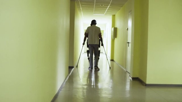Dolly shot. Young disable man walking in the robotic exoskeleton in the rehabilitation clinic.