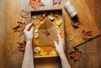 Gift wooden empty box full of autumn leaves. Autumn gifts. Top view on a wooden table