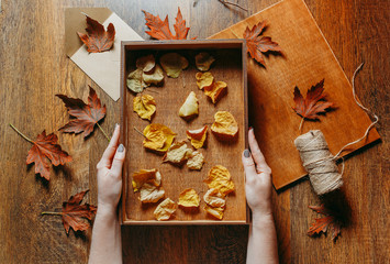 Gift wooden empty box full of autumn leaves. Autumn gifts. Top view on a wooden table