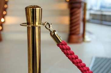 Goldener Absperrständer mit roter Kordel in einem luxuriösen Foyer Nahaufnahme
