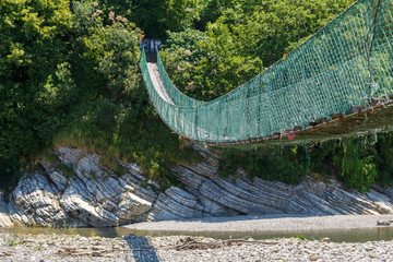 Wooden suspension bridge across a wide mountain river