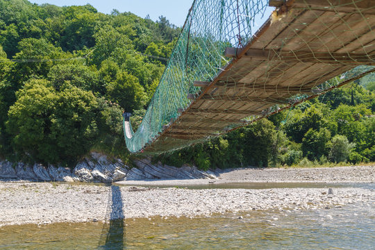 Long pedestrian suspension bridge across the mountain river Bzyb