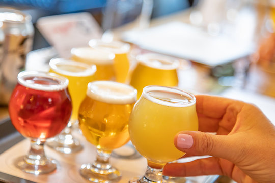 Female Hand Picking Up Glass of Micro Brew Beer From Variety on Tray