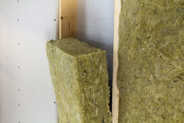 Close-up of wooden frame for future walls insulated with rock wool and fiberglass insulation staff...