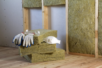 Rock wool and fiberglass insulation staff material for cold barrier. Tools for work with glass wool: protective goggles, glasses and mask. Warm home, economy, construction and renovation concept.