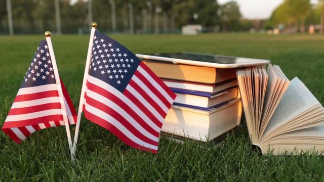 Books and the US flag on the grass. Study in America.