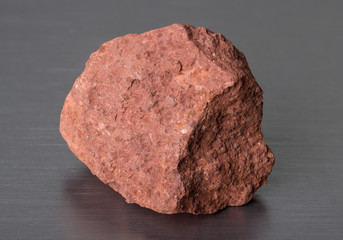Specimen of mineral stone bauxite on gray background. Bauxite ore is the main source of aluminium. 