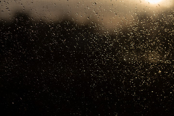 Fototapeta na wymiar Rain outside the window during sunset. Bright texture of water droplets