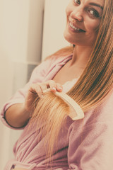 Fototapeta premium Woman combing her long hair in bathroom