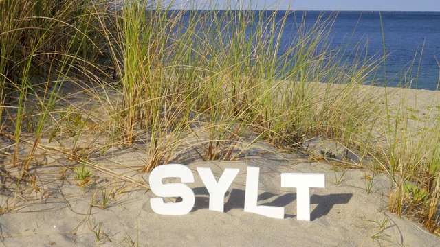Sylt D&uuml;nen Landschaft mit Strandhafer  mit Sylt Buchstaben und Blick auf das Meer