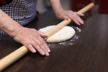 Senior woman hands knead dough on a table in her home kitchen