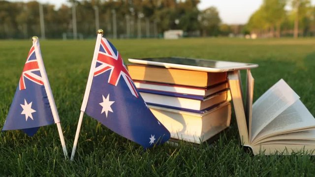 Australian flag and books on the grass. Education in Australia.