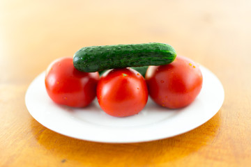 fresh tomato and cucumber in a plate on a brown table