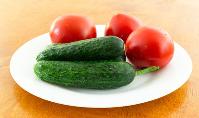 fresh tomato and cucumber in a plate on a brown table