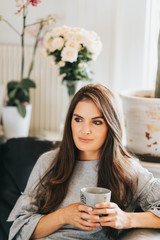 Young beautiful woman resting on the couch, holding cup of tea